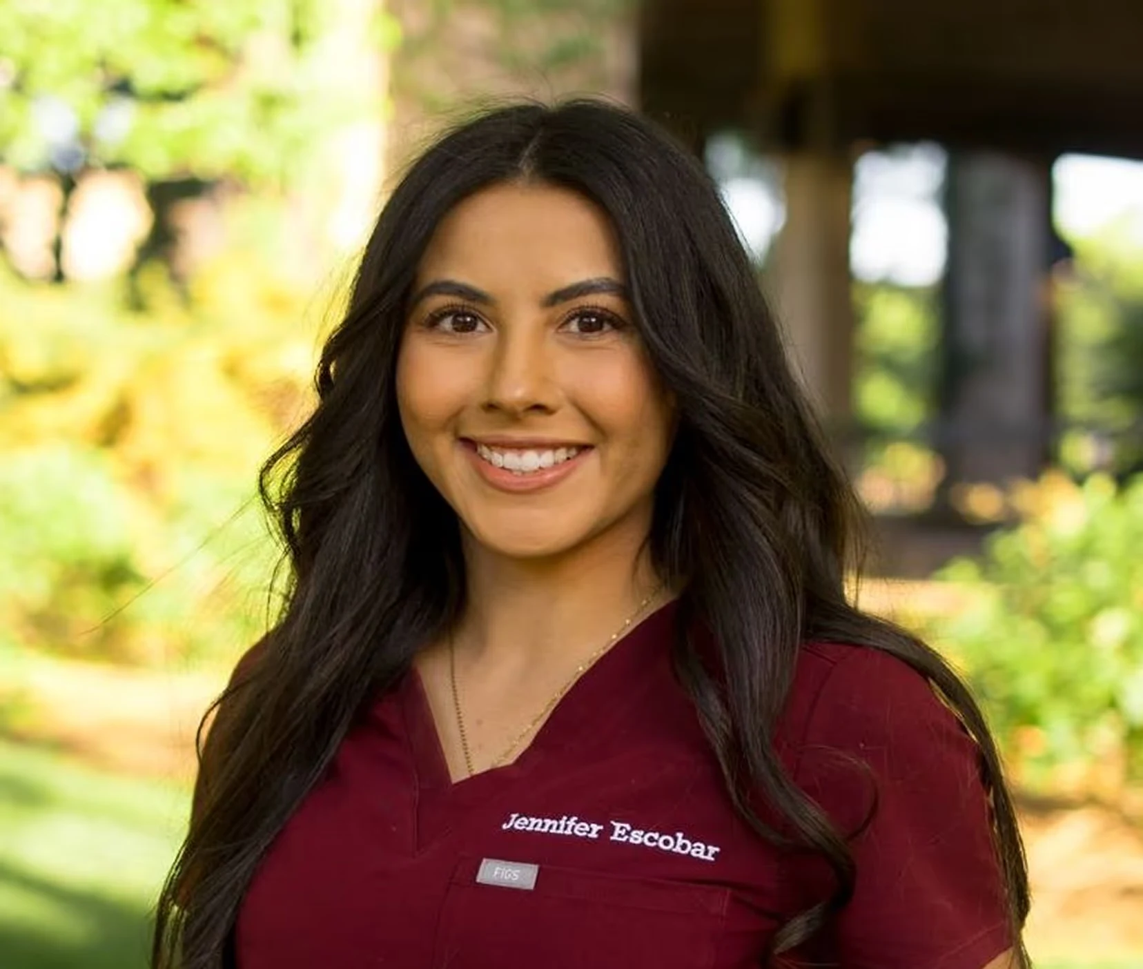 Dr. Jennifer Escobar, DDS, smiling outdoors in scrubs