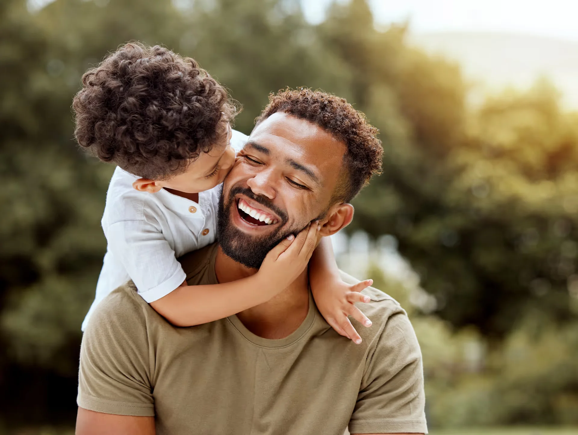 Father and young son embracing outdoors, both smiling